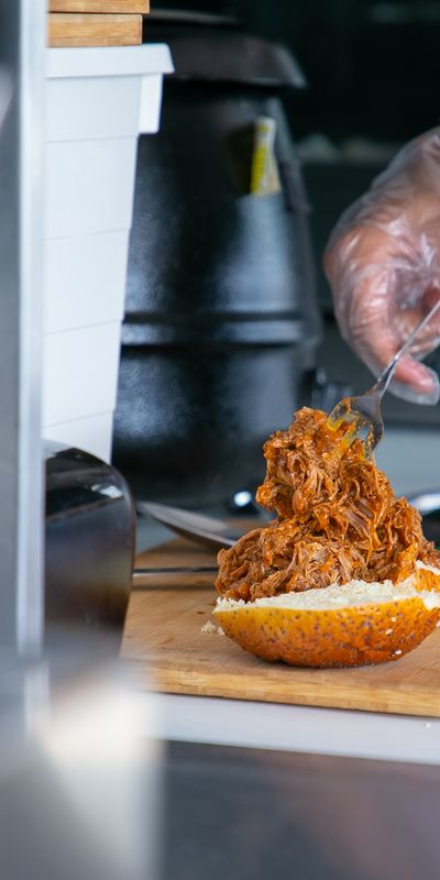 Pulled pork being piled onto a bun in the kitchen